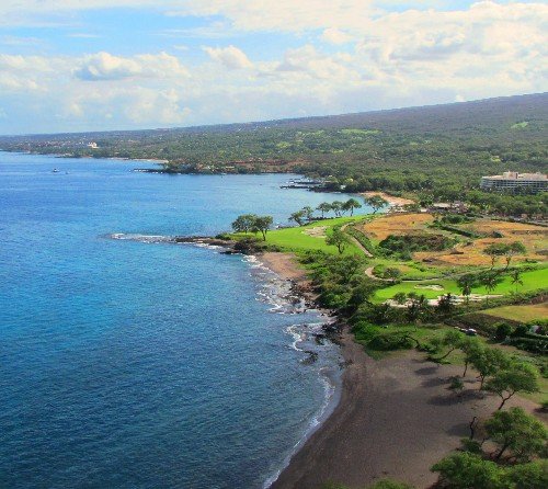Aerial view of the South Maui coastline meeting green resort land